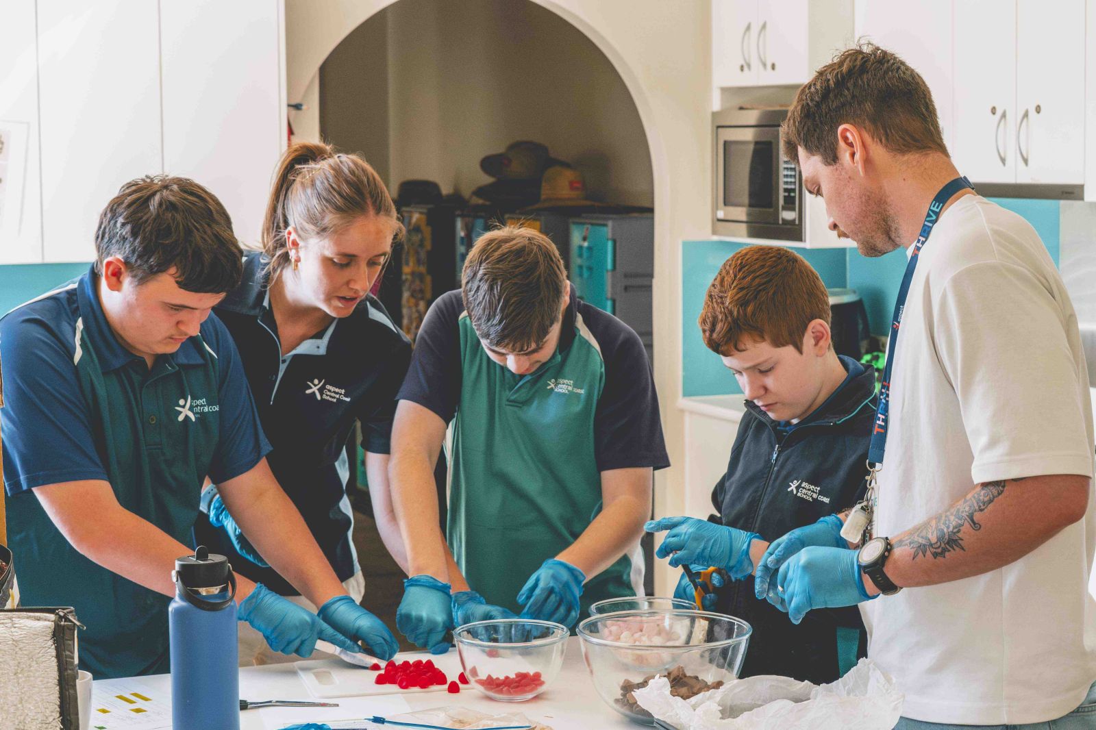Students and teacher preparing food in kitchen class